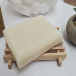 a bar of bergamot coconut oil soap on a wood soap dish