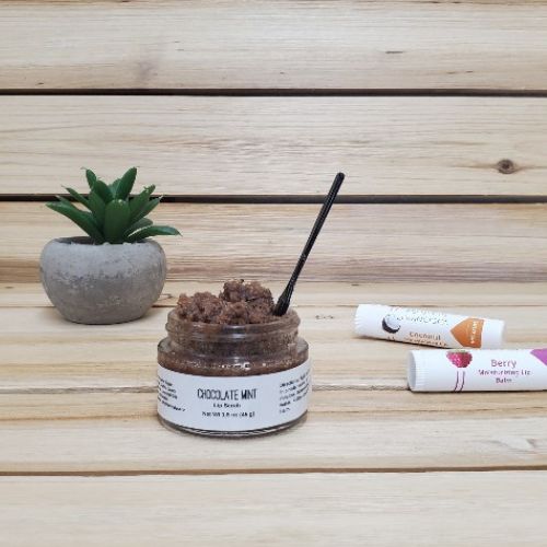 Chocolate Mint Lip Scrub open lid next to plant and lip balm