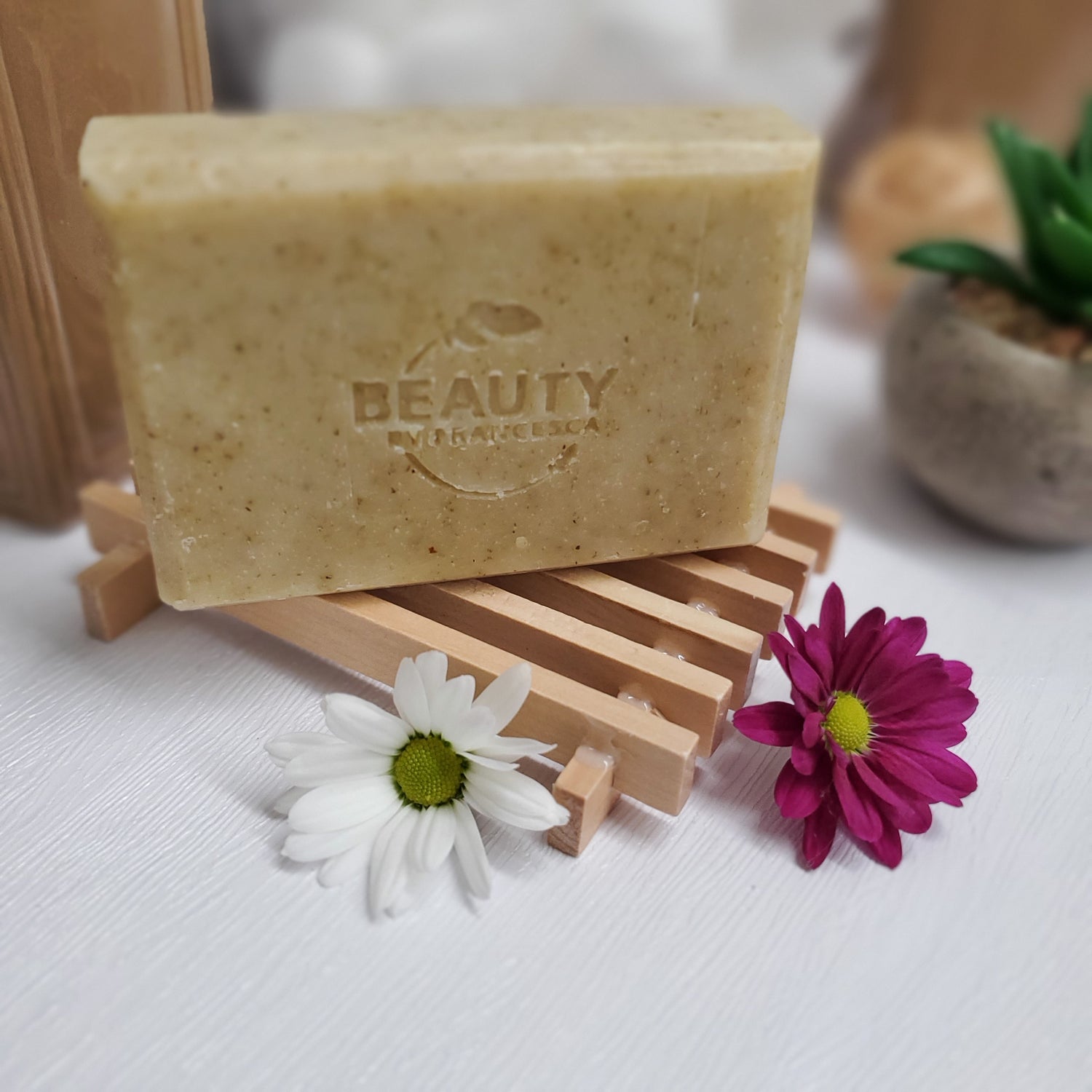 Chamomile Calendula Handmade Soap on top of wooden soap dish near plant