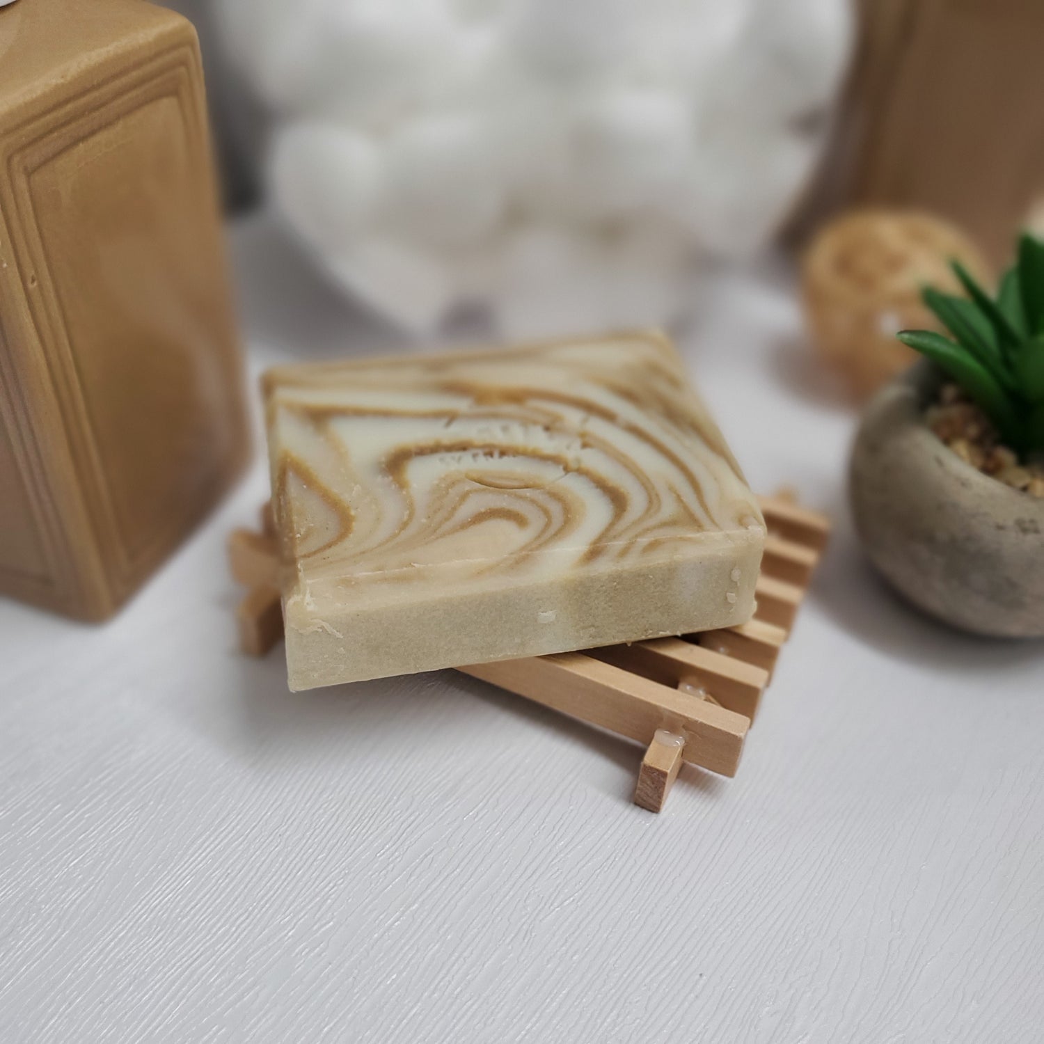 Eucalyptus Orange Handmade Soap on top of wooden soap dish near plant