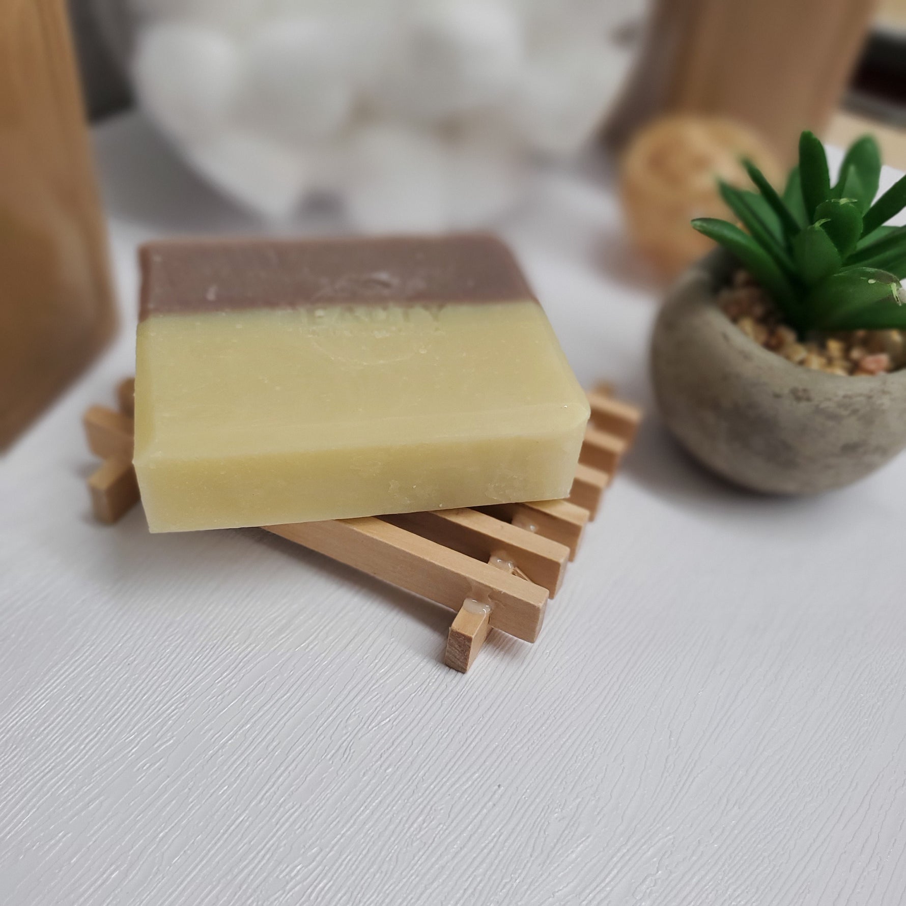 Lavender Handmade soap on a wood dish displayed near plant